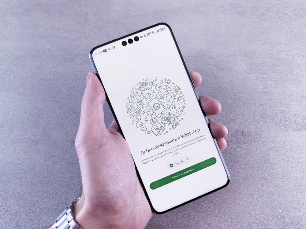 A hand holding a smartphone showing the WhatsApp welcome screen while choosing the right tool for a growing business